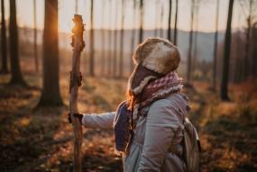 a woman in a forest with sunset in the background